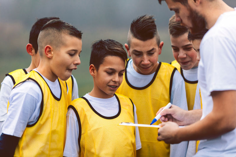 A coach going through a plan with young players in training bibs.