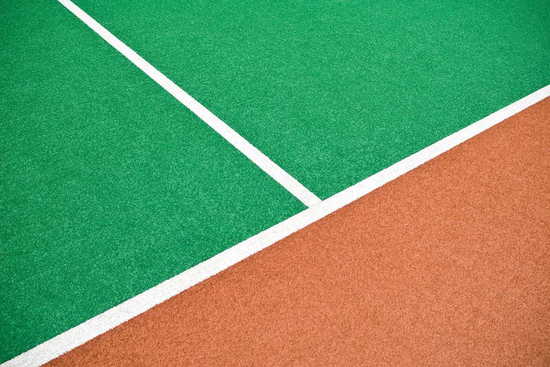 White court lines dividing green and terracotta playing surfaces.